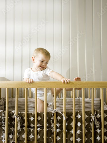 Photo: "USA, Utah, Provo, Baby boy (18-23 months) climbing in crib" "USA, Utah, Provo, Baby boy (18-23 months) climbing in crib"