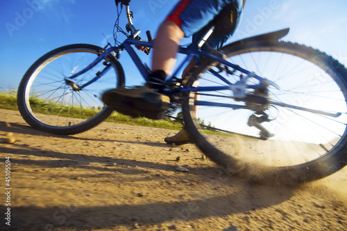 Photo: Low section of man stopping bike on dusty road Low section of man stopping bike on dusty road