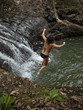 "Costa Rica, Young woman jumping into pool by waterfall"