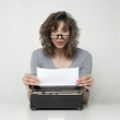 Studio shot of surprised woman looking at paper in typewriter