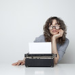 Studio shot of bored woman sitting at table with typewriter
