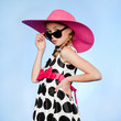 "Studio portrait of elegant girl (10-11) wearing hat, sunglasses and dress"