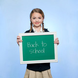 Photo: "Studio portrait of girl (10-11) holding green chalkboard with text ""Back to school""" "Studio portrait of girl (10-11) holding green chalkboard with text ""Back to school"""