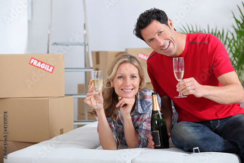 Photo: Couple holding champagne glasses boxes in background Couple holding champagne glasses boxes in background