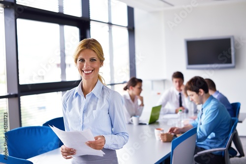 Photo: business woman with her staff in background at office business woman with her staff in background at office