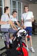 Man Holding Digital Tablet While Friends Exercising On Spinning