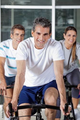 Photo: Three People On Exercise Bikes Three People On Exercise Bikes