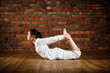Girl exercising yoga against brick wall