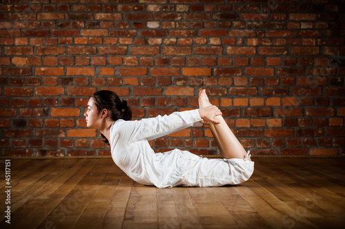 Photo: Girl exercising yoga against brick wall Girl exercising yoga against brick wall