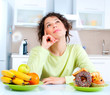 Diet. Beautiful Young Woman choosing between Fruits and Sweets