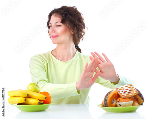 Photo: Diet. Beautiful Young Woman choosing between Fruits and Sweets Diet. Beautiful Young Woman choosing between Fruits and Sweets