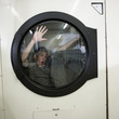 man inside a commercial clothes dryer at a laundromat
