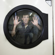 man inside a commercial clothes dryer at a laundromat