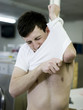 man putting on a shrunken t-shirt