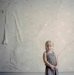 "USA, Montana, Bannack, Girl (2-3) posing against wall with peeling wallpaper"