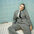 "USA, Utah, Salt Lake City, Mid adult man wearing suit lying down at corner"