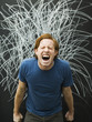 Studio shot of man yelling with chalk scribble on blackboard
