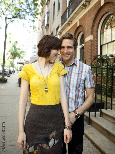 Photo: "USA, New York, New York City, Portrait of young couple in front of apartment building" "USA, New York, New York City, Portrait of young couple in front of apartment building"