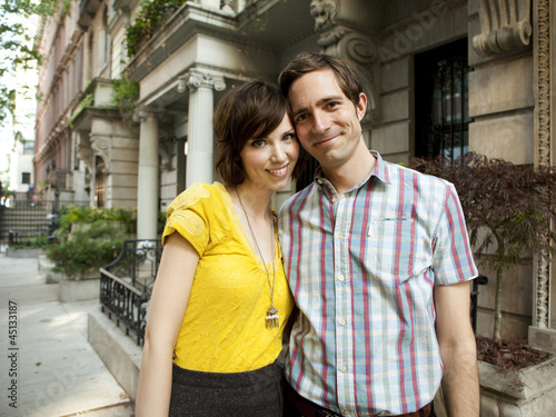 Photo: "USA, New York, New York City, Portrait of young couple in front of apartment building" "USA, New York, New York City, Portrait of young couple in front of apartment building"