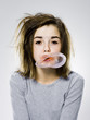 girl with a messy appearance popping a bubble gum bubble