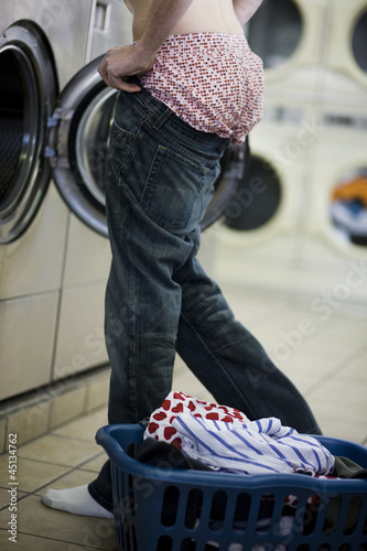 Photo: man putting on jeans at the laundromat man putting on jeans at the laundromat