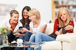 4 girls with smartphones on the sofa