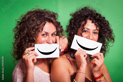 Photo: Two Young Women with Smiley Emoticon on Green Background Two Young Women with Smiley Emoticon on Green Background