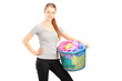 Photo: Young smiling woman holding a laundry basket full of clothes Young smiling woman holding a laundry basket full of clothes