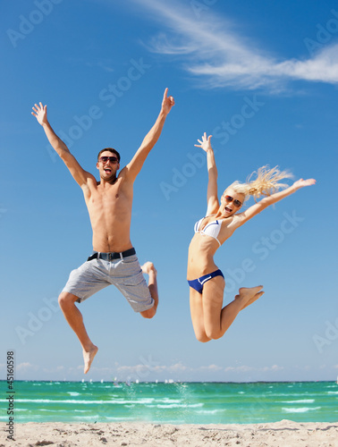 Photo: happy couple jumping on the beach happy couple jumping on the beach
