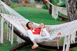 outdoors in a white hammock resting father and son in red shirts