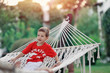 boy in a red shirt and white pants playing in a hammock