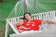 outdoors in a white hammock resting father and son in red shirts