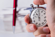 Stopwatch in hand on background of paper cards