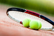 Tennis racket with balls on clay tennis court