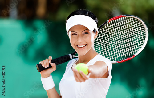 Photo: Woman in sportswear serves tennis ball. Tournament Woman in sportswear serves tennis ball. Tournament