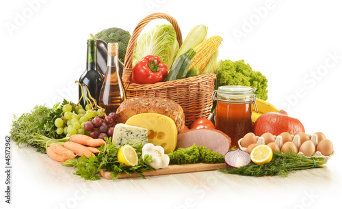 Photo: Composition with groceries in wicker basket on kitchen table Composition with groceries in wicker basket on kitchen table