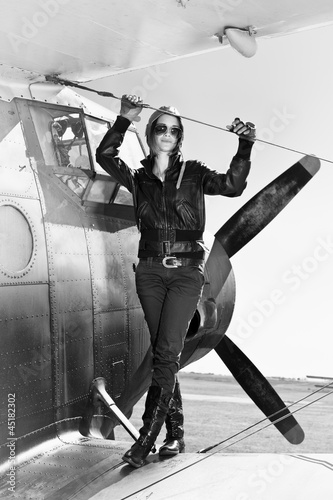 Photo: Beautiful girl in black jacket standing on a war aircraft. Beautiful girl in black jacket standing on a war aircraft.