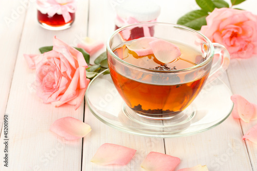 Photo: cup of tea with roses and jam on white wooden table cup of tea with roses and jam on white wooden table