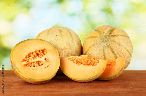 Photo: Cut melon on wooden table on green background Cut melon on wooden table on green background