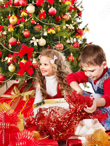 Photo: Children with gift box near Christmas tree. Children with gift box near Christmas tree.