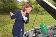 Cute woman checking level of oil on a car engine dipstick