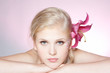 Foto: Beautiful young woman face with pink fresh flower Beautiful young woman face with pink fresh flower