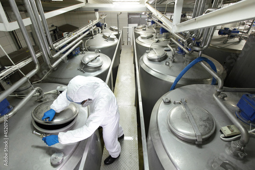 Photo: Worker closing industrial process tank in plant Worker closing industrial process tank in plant