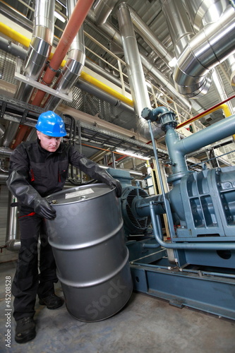Photo: Oil Worker in uniform dealing with silver oil barrel Oil Worker in uniform dealing with silver oil barrel