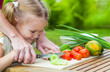 mother teaches daughter  knife cut cucumber
