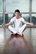 Young Man Meditating On Wooden Floor