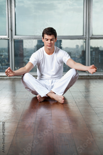 Photo: Young Man Meditating On Wooden Floor Young Man Meditating On Wooden Floor