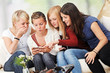 4 girls with smartphones on the sofa