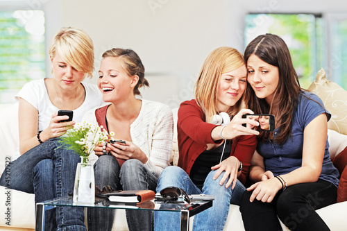 Photo: 4 girls with smartphones on the sofa 4 girls with smartphones on the sofa