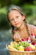 Cute girl wih fresh fruit basket outdoors.